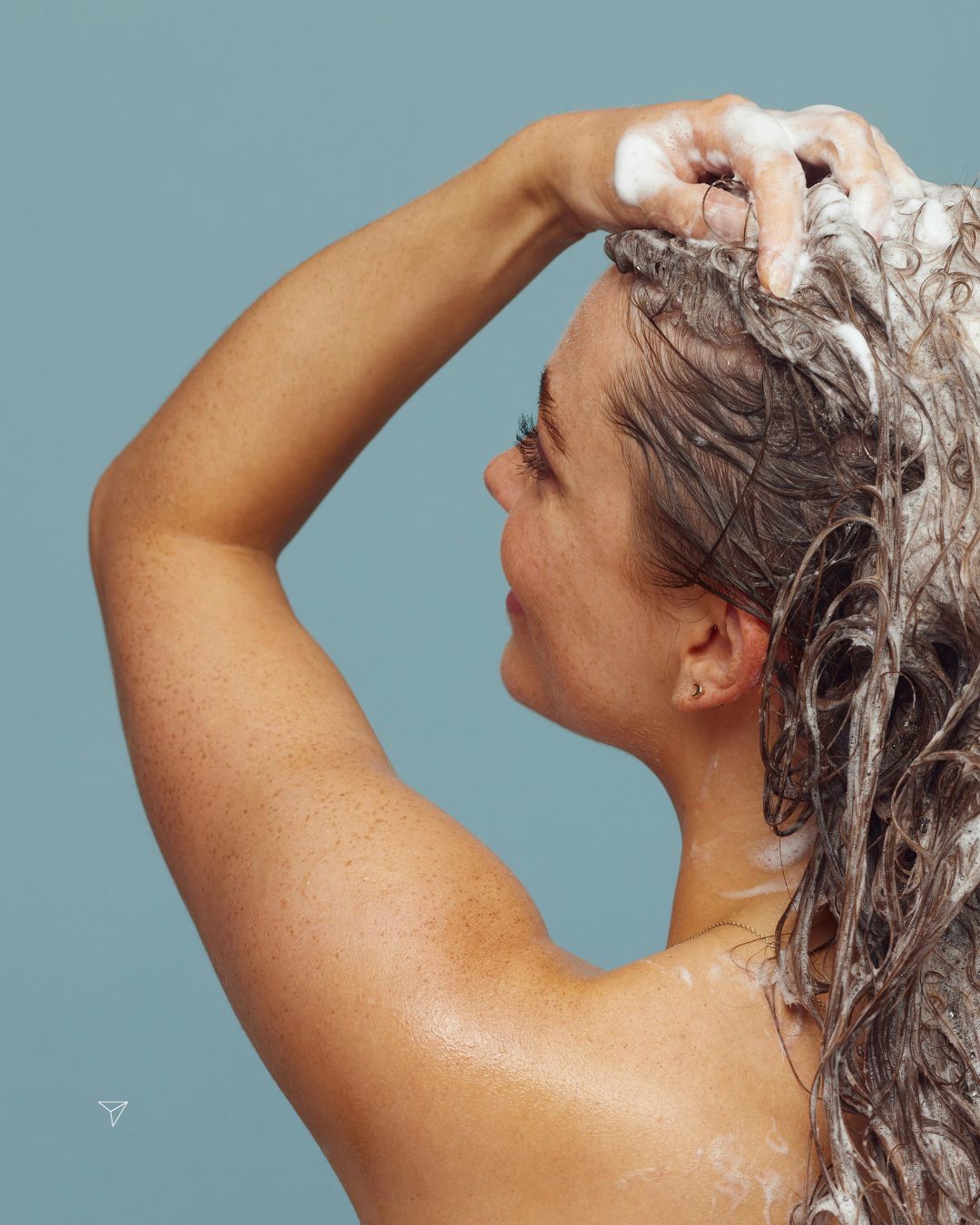 Woman lathering shampoo into wet hair, illustrating how human shampoo is formulated for human skin